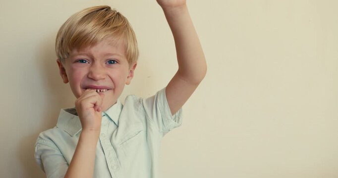 A young boy shows a chocolate candy to the camera with one hand, and with the other points to his wiggly tooth, making a No gesture.