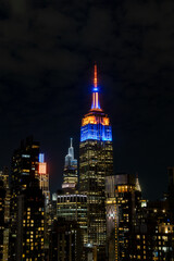 Naklejka premium New York, NY- May 21 2026: Manhattan skyline with the Empire State Building in New York Knicks colors