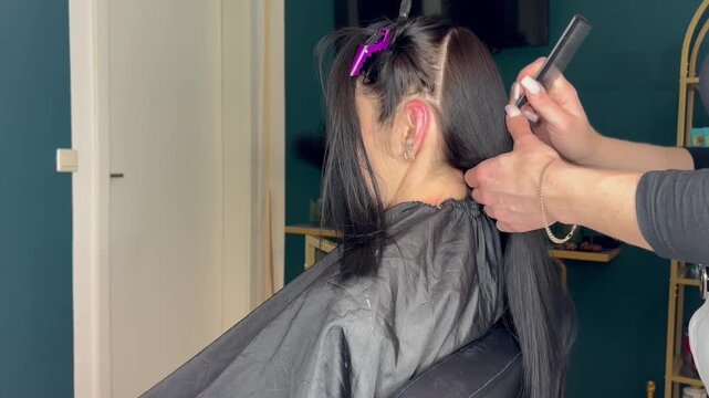 Hairdresser Using Flat Iron on Long Black Hair Extensions Close Up. High quality FullHD footage