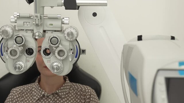 A positive female patient undergoes a professional vision check and refraction test using advanced ophthalmic equipment. This high-value commercial stock imagery represents preventative healthcare, pr