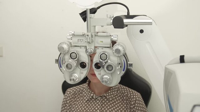 A positive female patient undergoes a professional vision check and refraction test using advanced ophthalmic equipment. This high-value commercial stock imagery represents preventative healthcare, pr