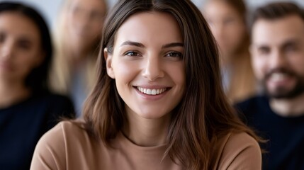 Fototapeta premium Young woman smiling in a close up headshot with a blurred diverse team in the background, conveying cheerful, confident teamwork, inclusion and professional collaboration in office