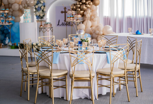 Elegante mesa de celebraci&oacute;n con sillas doradas y decoraci&oacute;n de globos para evento infantil de bautizo