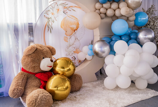 Decoraci&oacute;n de bautizo infantil con oso de peluche, globos azules y angelito en elegante fondo tem&aacute;tico