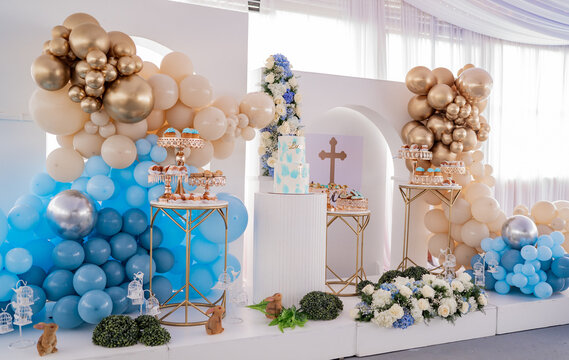 Elegante decoraci&oacute;n de bautizo con pastel tem&aacute;tico, globos azules y dorados y mesa de postres en sal&oacute;n de eventos