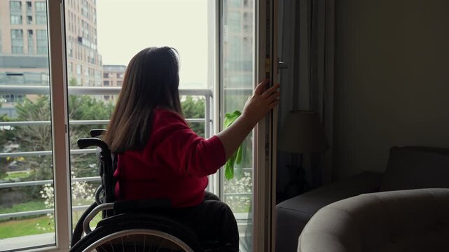 Woman Using Wheelchair Cleaning Balcony Window in Modern Apartment