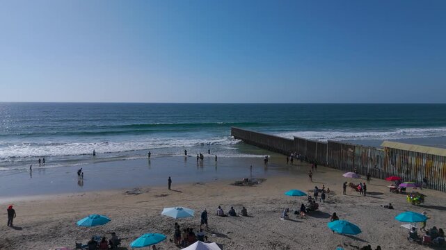 Aerial Perspective of Pacific Coast Beach and International Border Fence Stretching Into Sea in Tijuana Mexico