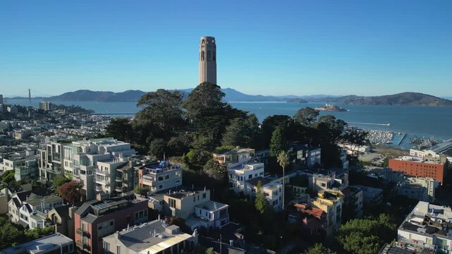 Aerial drone footage of Coit Tower in San Francisco, California, captured from above with stunning panoramic views of the city skyline, Telegraph Hill, the San Francisco Bay, and surrounding urban