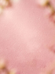 Fototapeta premium Romantic spring cosmetic product staging background with a textured pink backdrop and blurry floral framing for clean copy space, ideal for a feminine skincare brand marketing banner.