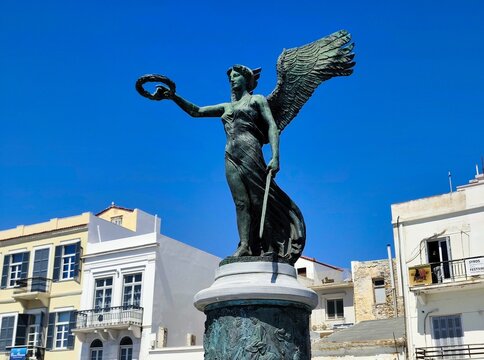 Photo of the National Resistance Monument in Ermoupoli, Syros island, Greece, depicting a winged female figure triumphantly holding a laurel wreath.