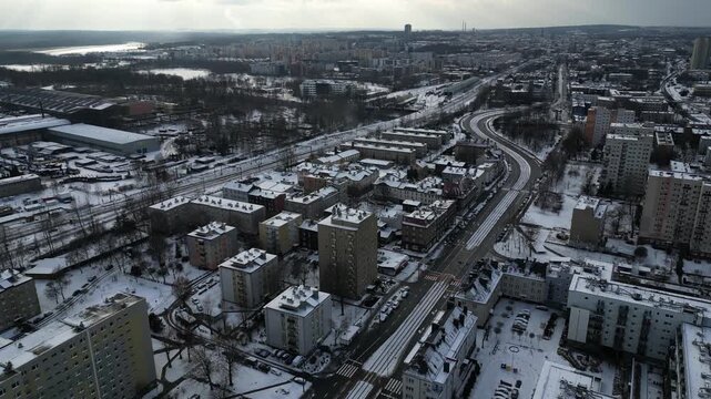 Aerial view of a snow-covered city during winter, slow drone flight over residential neighborhood and apartment blocks under dramatic sky, Katowice, Poland.