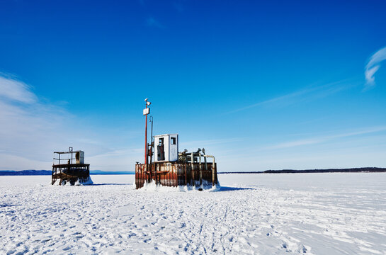 two industrial water intake structures (often referred to as intake cribs or pump towers) standing out of the completely frozen surface of Lake Champlain, Burlington, Vermont