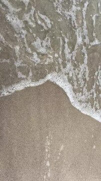 Aegean Sea waves washing onto sandy shore top view. Sea surf rolling onto sandy shoreline in the Aegean Sea