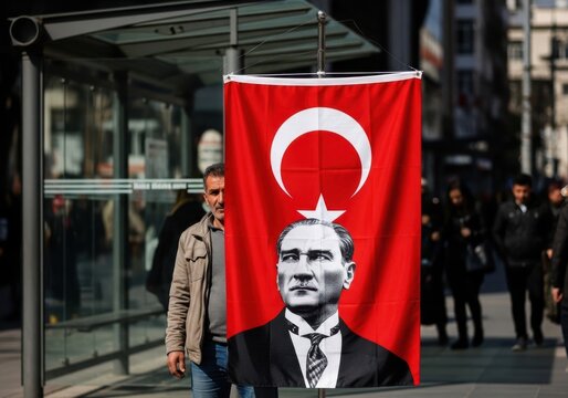 Man walking past a turkish flag featuring a portrait of mustafa kemal ataturk