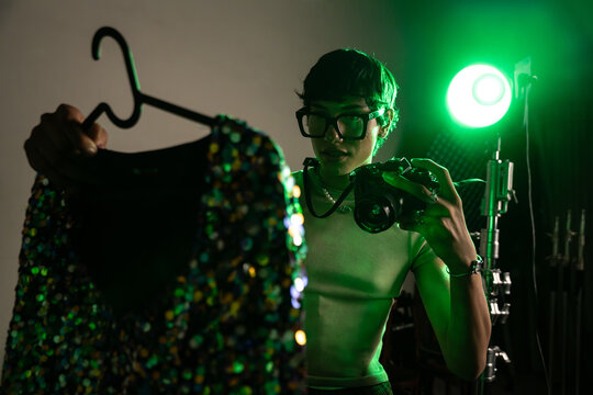 Photographer in studio inspecting sequined dress on hanger