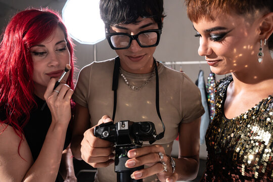Fashion photoshoot crew reviewing camera shots backstage