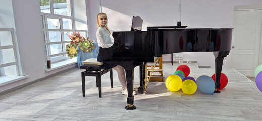 A happy ten-year-old girl plays the piano and looks at the audience. © ANASTASIIA