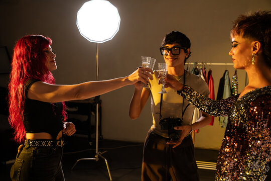 Fashion photoshoot crew celebrate with toast in studio