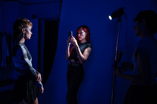 Fashion studio crew capturing model with smartphone light