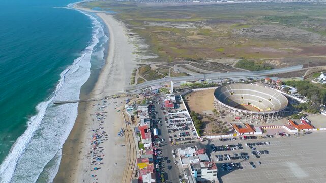 Aerial Flight Over Monumental Bullring and Coastal Border Wall Infrastructure in Tijuana Mexico. The video sequence beautifully centers the massive circular structure of the Monumental Bullring.