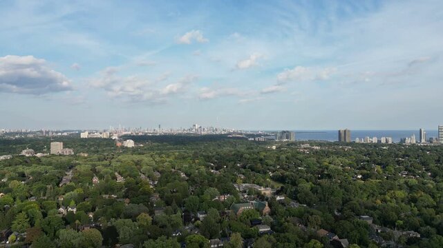 Aerial over the Bloor Street West area, over the Kingsway neighborhood of Toronto, Ontario, Canada. Flying northwest with the downtown core Toronto skyline, Mimico and Lake Ontario in the distance. 