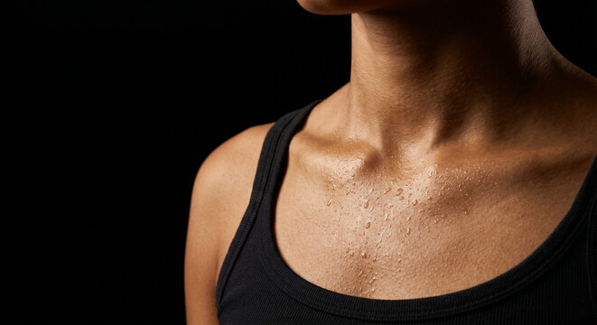 Close up of wet athlete chest and collarbone with sweat drops on black background