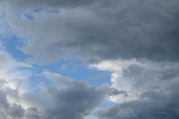 Obraz premium Overcast sky with dense gray clouds and small gaps of blue sky visible between the dark clouds