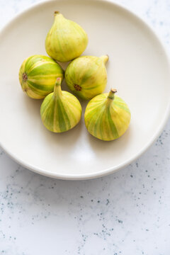 Panache tiger striped figs on a white plate with neutral background