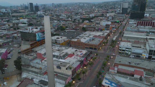 Aerial Dusk Flight of Main Avenue and Monumental Arch Near US-Mexico Border in Tijuana, Mexico.