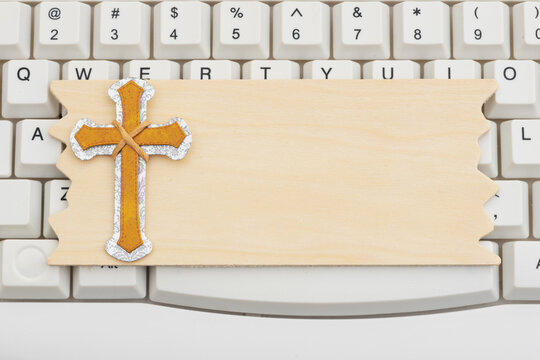 Gold cross on a blank wood sign on white computer keyboard for announcements