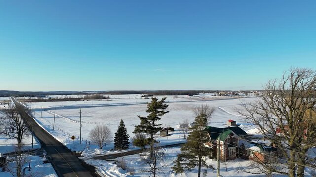 Aerial shot over Caledon, Ontario, Canada on a cold winter afternoon after a heavy snowfall on March 4, 2023. Lifting up, looking south over the Inglewood area overlooking farms and agricultural land.