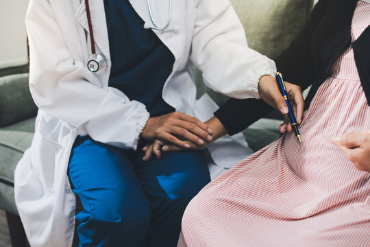 Pregnant woman having her belly examined by a doctor with a stethoscope in a clinic room highlighting a medical checkup, pregnancy health, and prenatal care