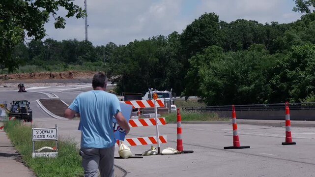 Man holding No Data Centers sign construction site barricades protesting AI tech infrastructure power grid development environmental impact zoning