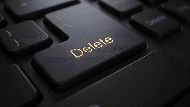 Close up macro view of a black computer keyboard key with the word delete printed in golden letters showing a textured surface and soft lighting