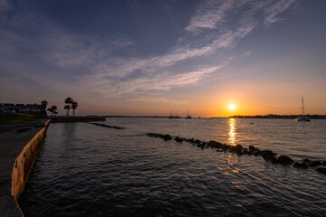 Obraz premium Sunrise and Sunset Over Historic St. Augustine, Florida. Castillo de San Marcos Silhouette with Palm Trees, Sailboats, and Bridge of Lions Reflecting on Matanzas Bay
