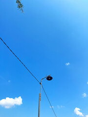 Obraz premium A lone street lamp stands tall under a clear blue sky with scattered clouds in an urban landscape scene outside during daytime