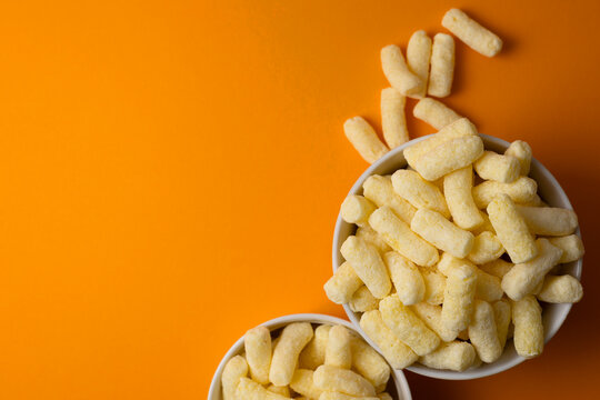 Crunchy Corn Puffs Closeup. Playfully Scattered Puffed Corn Pieces On Vibrant Surface For Advertisement
