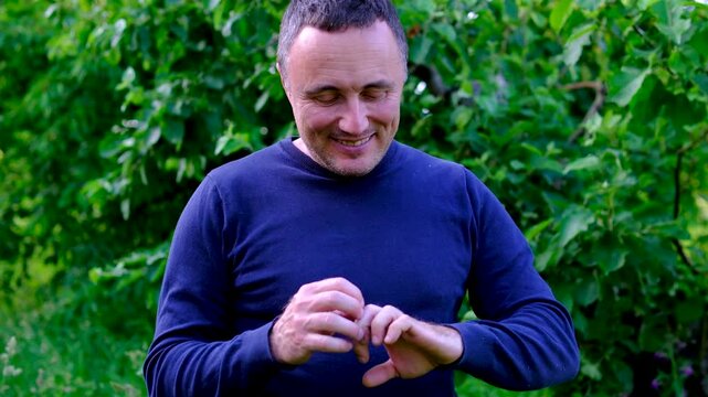 Looking over his fingers after physical labor a gardener notices signs of hard work and experience. A satisfied smile reflects pride accomplishment dedication and connection to outdoor life.
