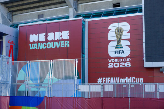 A large maroon BC Place wall carries the We Are Vancouver slogan, the FIFA World Cup 2026 logo with the trophy and a hashtag near Gate A, behind security fencing.