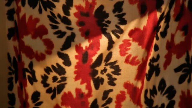 Close-up of a fabric with a bold floral pattern in red, black, and cream.