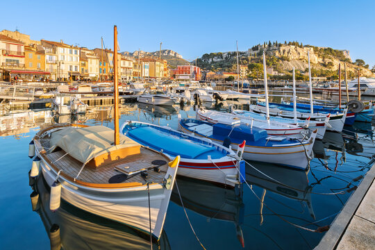 The charming French Riviera, seaside town of Cassis, France, with the medieval castle rising above the colorful old town and marina at dusk.