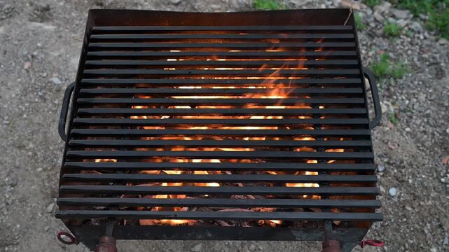 Fire burning in a barbecue grill, grates ready for cooking. Flames in a grill with cooking grates ready for grilling. Hot barbecue grill with fire.