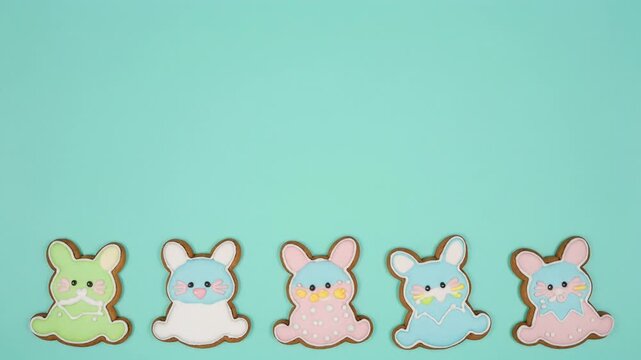 Five colorful Easter bunny shaped cookies arranged in a row on a light blue background.