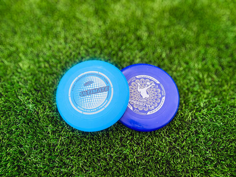 Springfield, Illinois, USA - May 20, 2026: An overhead view of blue ultimate frisbee flying discs stacked on a green artificial turf field, with the grass falling into a softly blurred background.