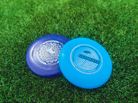 Springfield, Illinois, USA - May 20, 2026: A close-up shot of blue ultimate frisbee flying discs centered on a green artificial turf field with a softly blurred background.