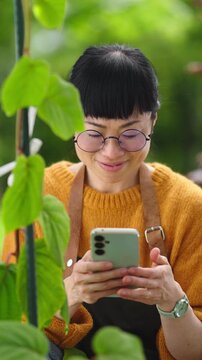 Using a smartphone to access gardening information and monitor plant care while working outdoors. Modern gardening concept combining digital tools, plant maintenance and everyday garden management.