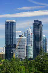 Fototapeta premium Vibrant skyline of Burnaby showcases modern high-rises against a brilliant blue sky in summer