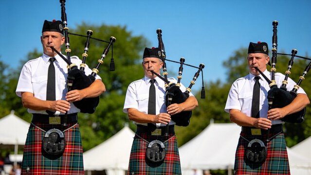 Three men playing bagpipes outdoors