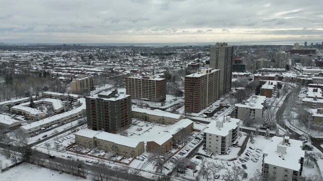 Aerial over Mississauga, Ontario, Canada on a cold winter morning after snowfall on March 4, 2023. Cooksville area towards Lake Ontario over condominiums and apartments.