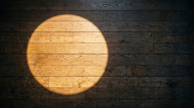 Bright circular spotlight illuminating dark textured wooden floorboards